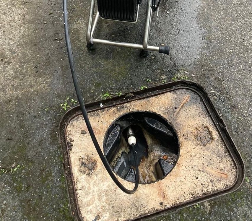 CCTV drain survey camera lowered into a chamber